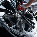Person cleaning a car wheel with a brush